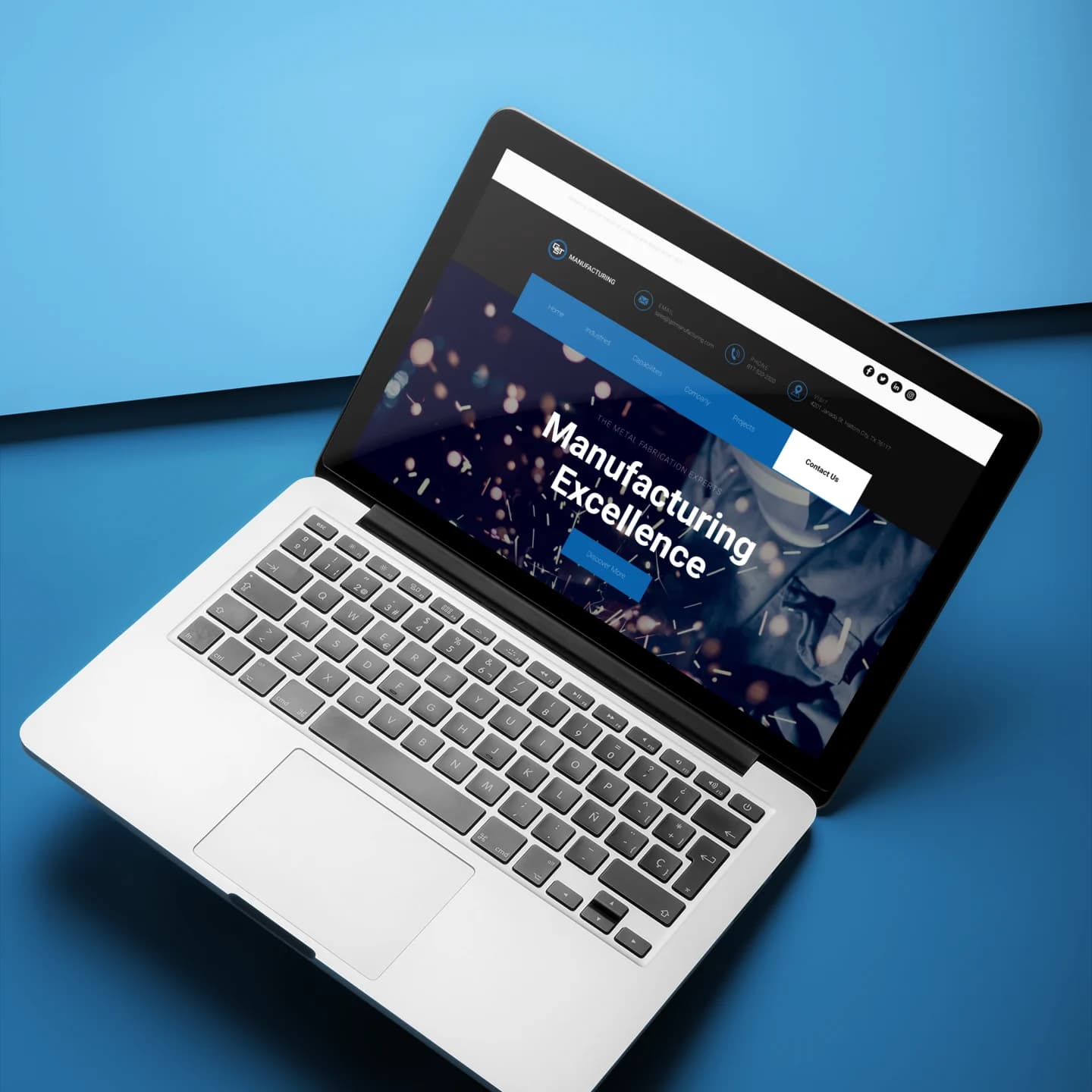 A MacBook Pro open on a two-color surface displaying the custom-designed, dark-themed GST Manufacturing website home page.