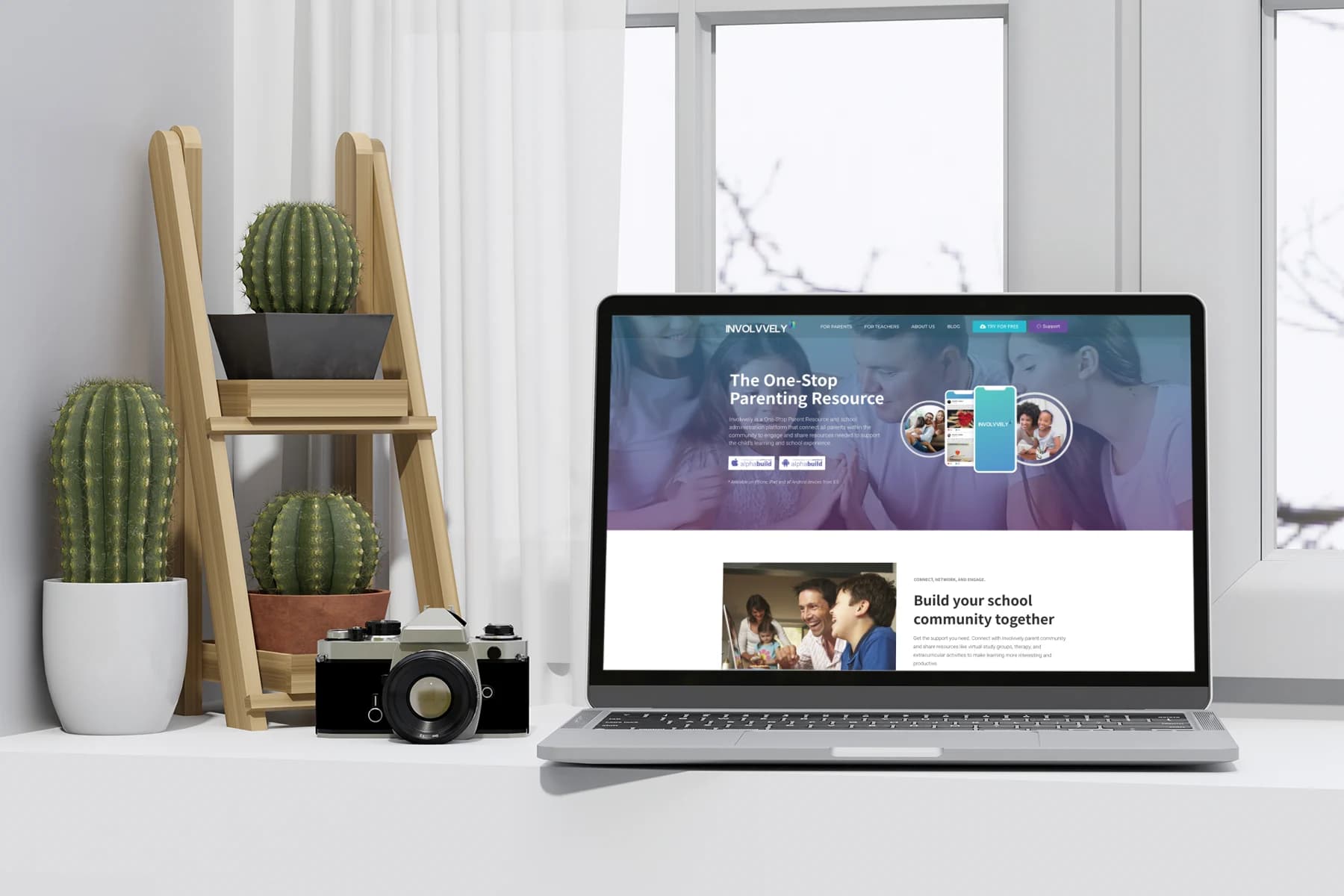 A MacBook Pro open on a white desk next to potted cactuses, displaying the custom-designed, light-themed website for the Involvvely parenting app.
