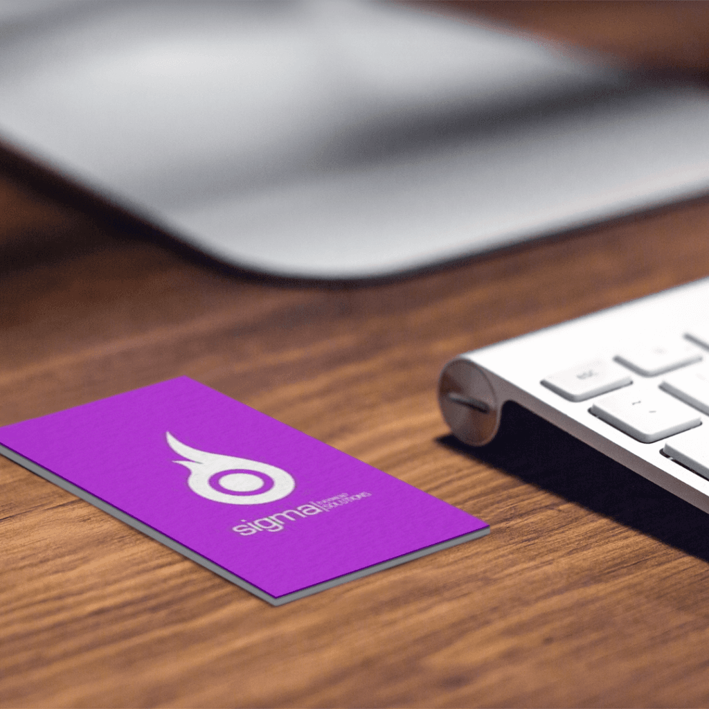 Sigma Payments business cards with purple branding on a wooden surface